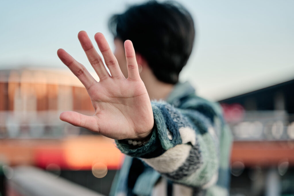 What to Do If Your Rental Application Is Rejected in Japan young asian man covering his face in a stop sign. young celebrity covering his face with the palm of his hand and looking away to avoid paparazzi.