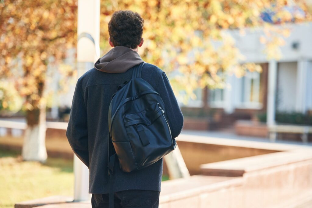 The First 30 Days in Japan: An International Student Checklist back view. young student is outside the university, in black clothes