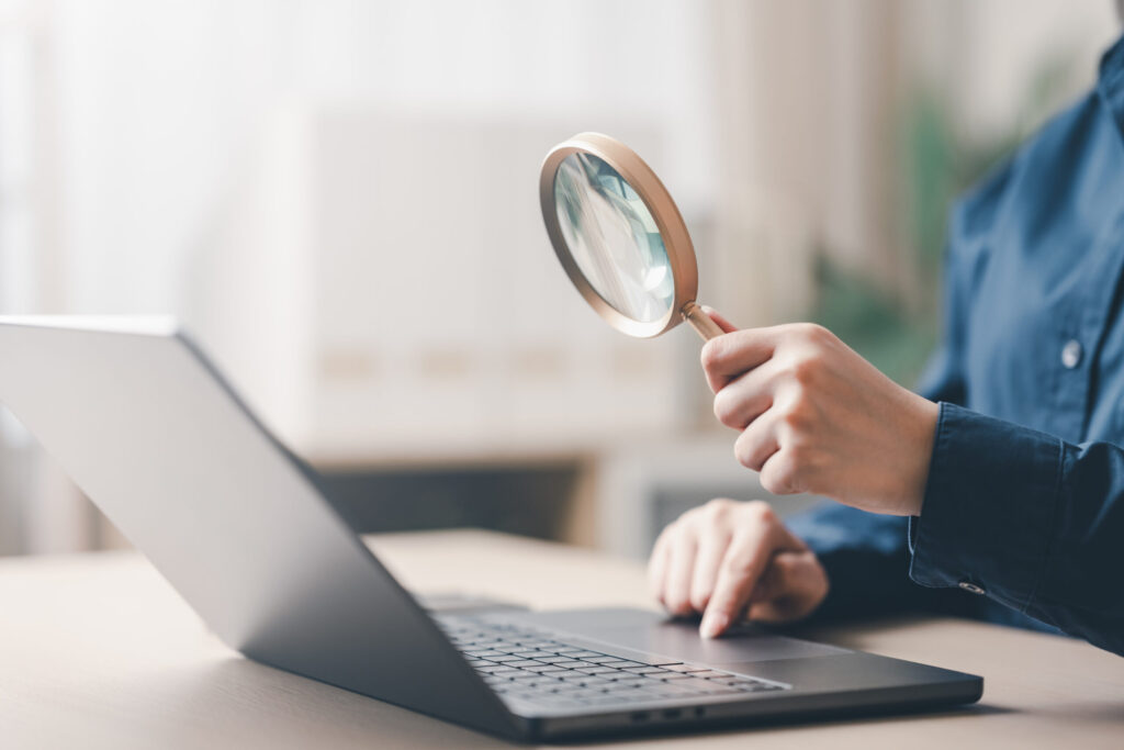 Rent Guarantor Companies in Japan Compared: What to Look For search, magnifying, research, focus, a person using a magnifying glass while working on a laptop, representing research, analysis, and information discovery concepts.