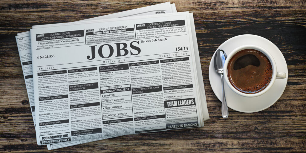 job classifieds ads newspaper and coffee cup on wooden table. jo