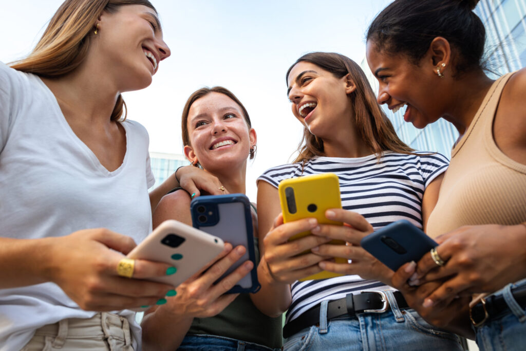 eSIM vs Physical SIM in Japan: Which Should You Choose? low angle view of happy multiracial group of young women friends laughing and having fun while using mobile phones.