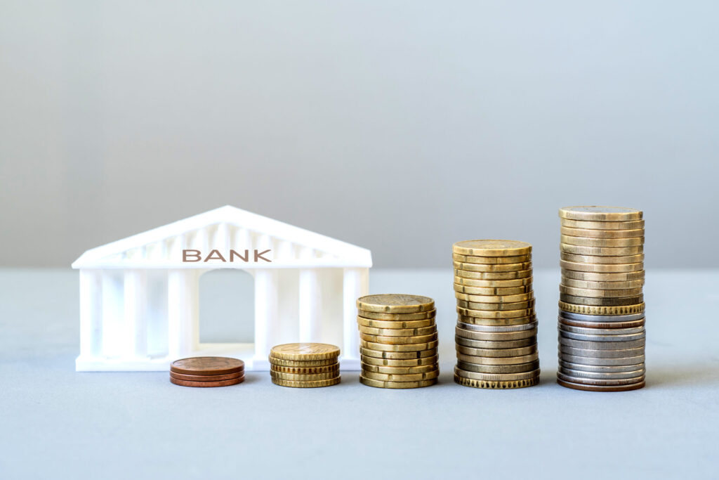 How to Open a Bank Account in Japan as a Foreigner model of a bank building with growing stacks of coins, financial growth