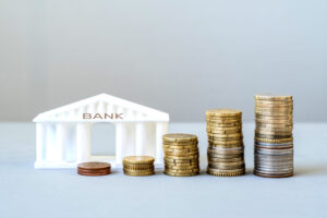 model of a bank building with growing stacks of coins, financial growth