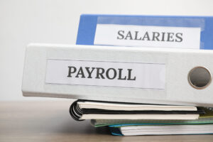 office folders with words payroll and salaries on wooden table,