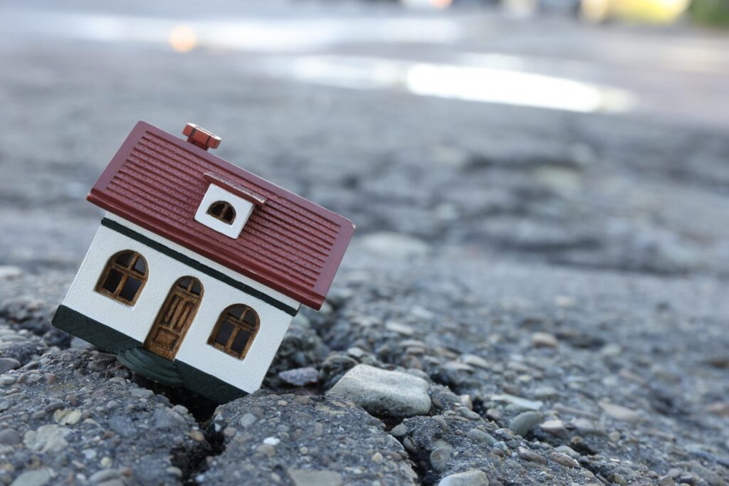 house model in cracked asphalt demonstrating earthquake disaster