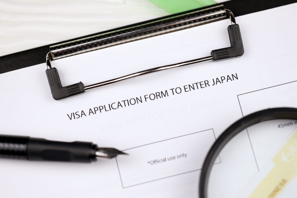 Japan's Immigration Changes in 2026: What Foreign Residents Need to Know visa application to enter japan on a4 tablet lies on office table with pen and magnifying glass