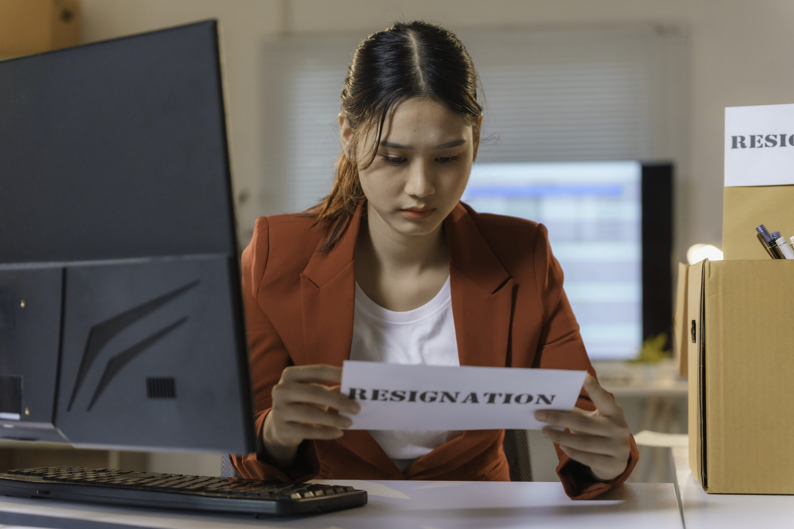 How to Resign From a Job in Japan: Notice Periods and Etiquette asian businesswoman holding resignation letter while packing belongings in box at office desk